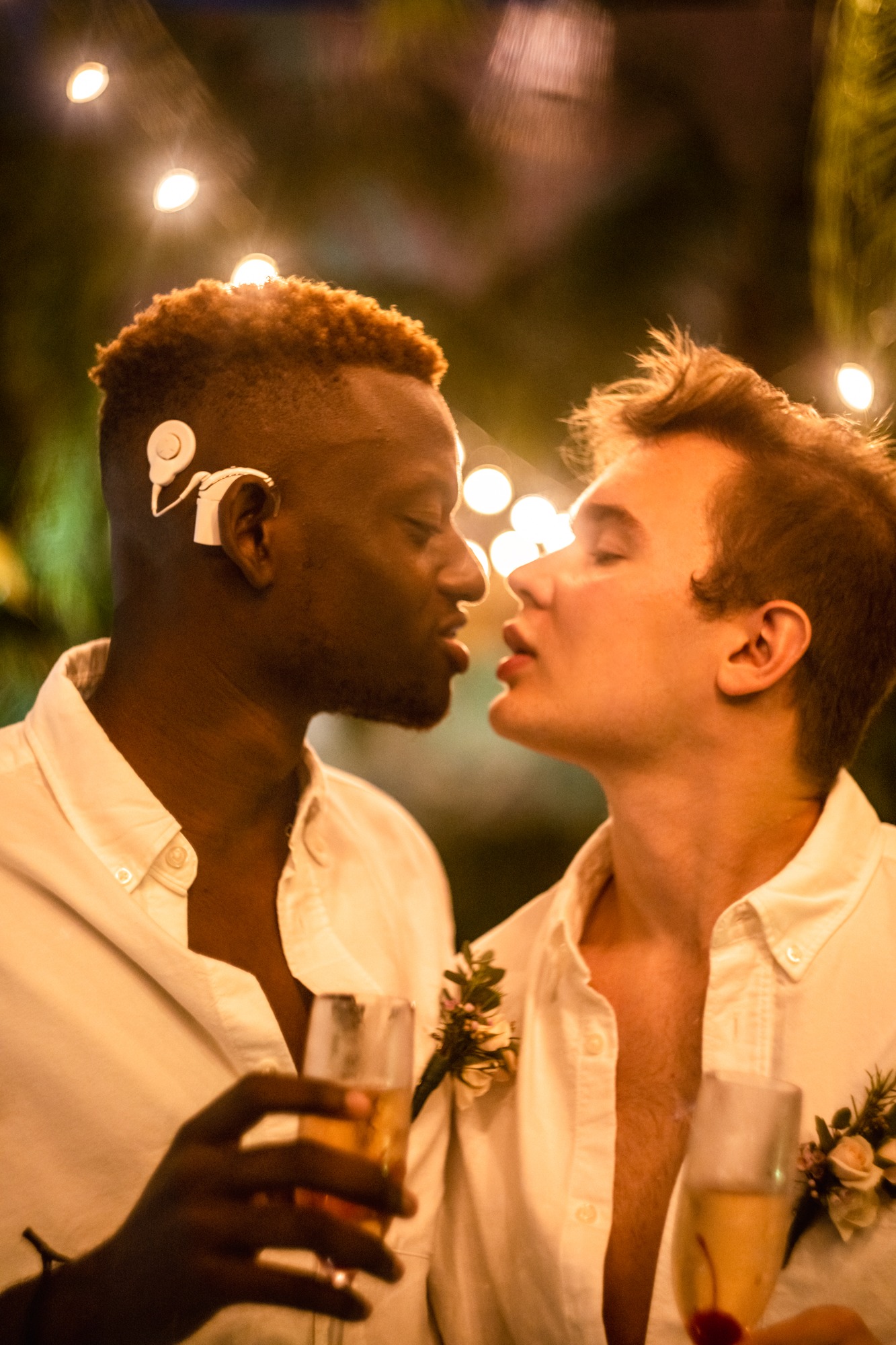 Two grooms sharing a kiss at a candlelit wedding reception, Riviera Maya
